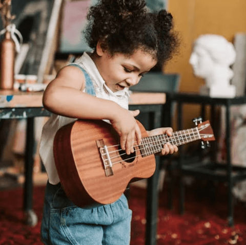 little girl plays a ukelele