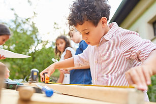 Child with measuring tape when measuring wood in the craftsman workshop at the holiday cam