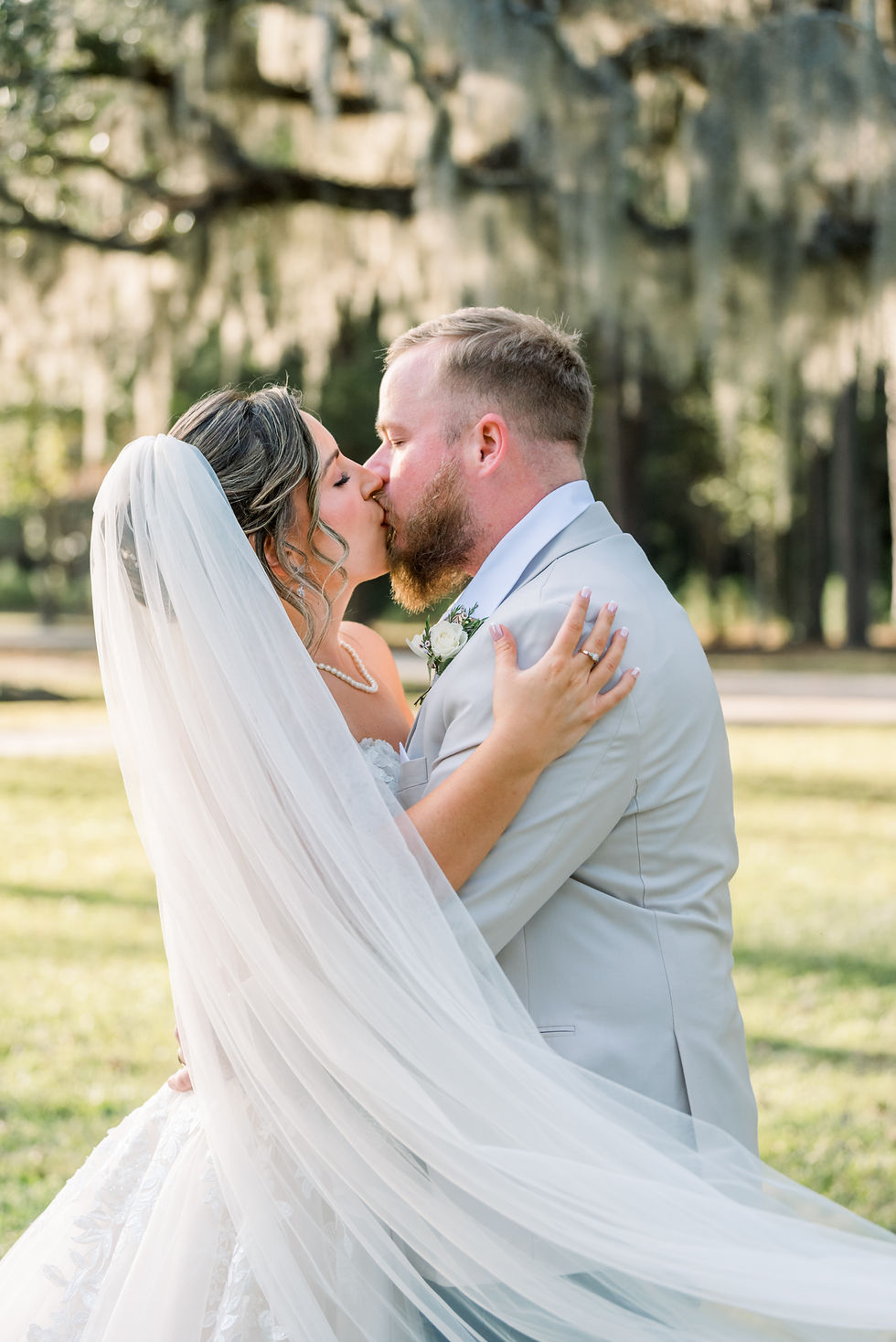 Bride and groom kiss with veil sweeping in the foreground at Old Homestead Farm