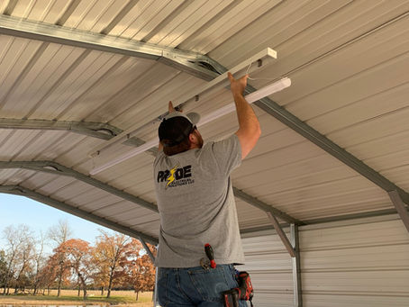 A local electrician in Paris TX hanging a light fixture.