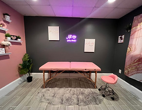 Pink beauty room at Creative Block ATL with massage table, neon sign, and soft decor—ideal for spa shoots, lashes, or facials