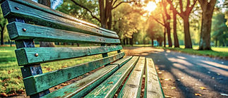 empty park bench, with a path leading into the distance as the sun sets