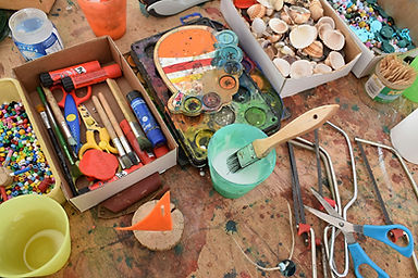 Malutensilien auf Tisch, Farben, Pinsel, Muscheln und mehr. Ferienkurse & Kurse.