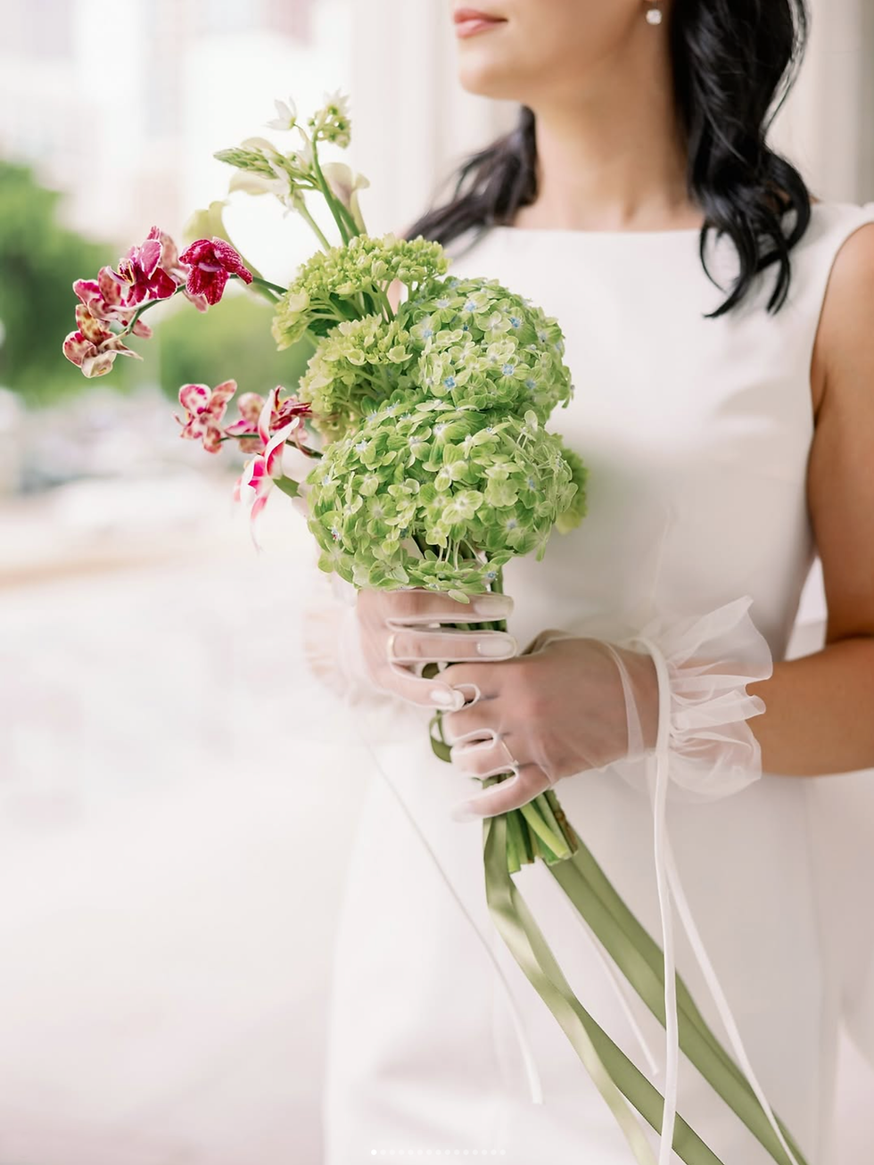 Bride holding a sculptural bouquet with green hydrangea and patterned orchids, illustrating refined floral design and thoughtful detail in a luxury wedding.