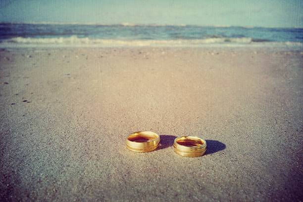 Two wedding bands laying on a sandy beach