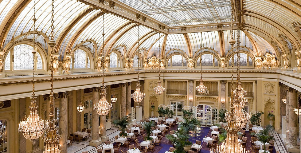 Grand historic hotel interior with chandeliers, vaulted glass ceiling, and strong architectural symmetry.
