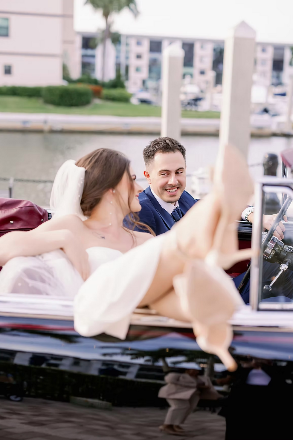 Bride and groom sharing a playful moment in a vintage convertible during an intimate destination wedding celebration in Naples, Florida.