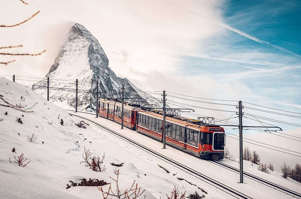 The Gornergrat mountain railway passing through deep snow with the cloud-capped Matterhorn rising behind it in winter