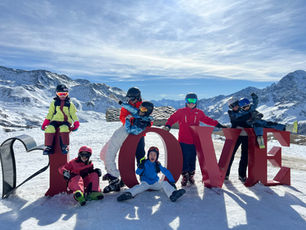 a happy family in zermatt poses for a photo over a sign that spells LOVE