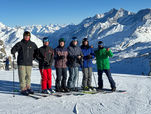 a group of happy people are standing on skis and smiling at the camera 