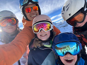 A ski guide and a group of children take a selfie close up