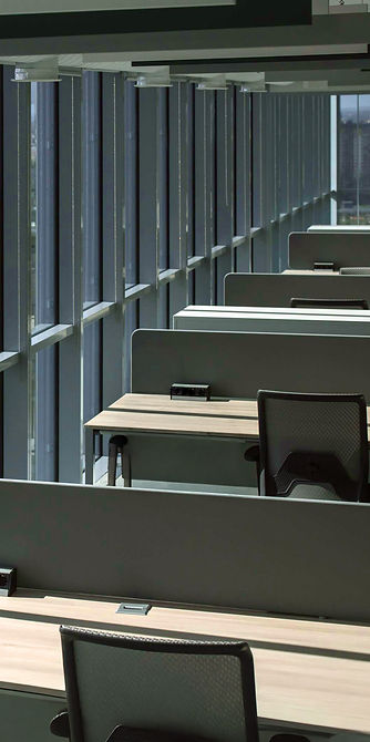 Urban office building with many desks and chairs with tall windows