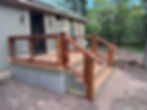 Deck and stairs with wooden railing and metal grid on a small house