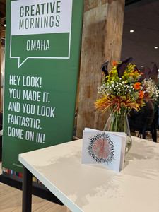 Notebook featuring artwork by Andrea Joy Pearson displayed at CreativeMornings Omaha.