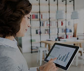 Woman using a tablet with graphs in front of a white board