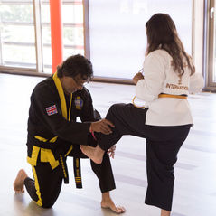 An instructor helping a student with her kick during a Choi Kwang Do class in Edgware