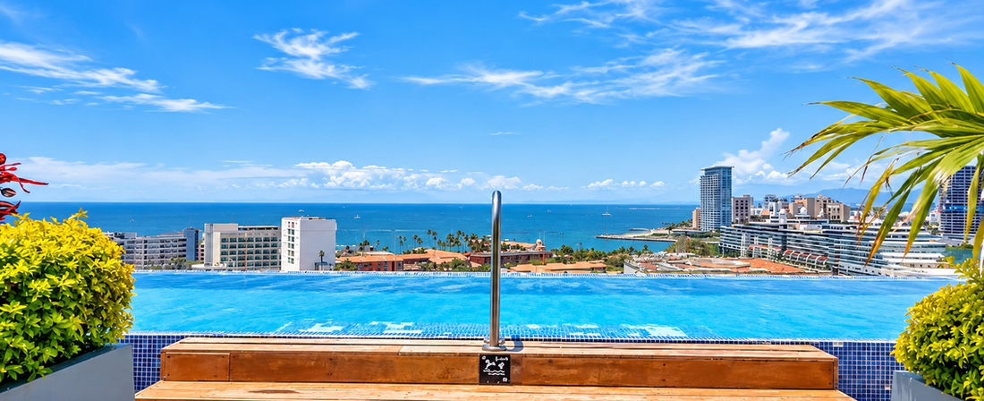 Alberca de Zoho Skies con vista panorámica al océano y la Zona Hotelera de Puerto Vallarta.