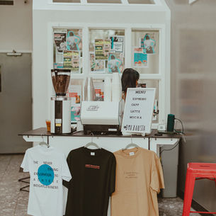 Coffee cart setup with t shirts hanging off of it.