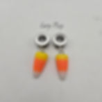 Pair of stainless steel tunnel plugs with dangling candy corn charms in yellow, orange, and white.