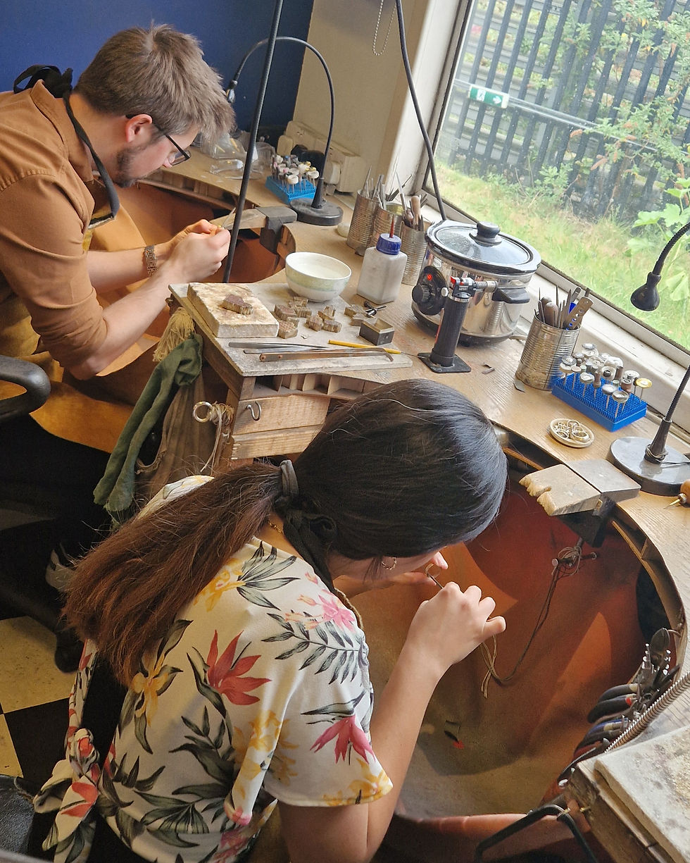 a couple at a jewellers bench making their own wedding rings in London bespoke jewellery workshop