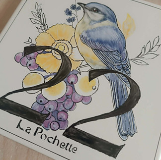 Plaque de maison artisanale en faïence, peinte à la main. Décor d’oiseau, couleurs vitrifiables et trois cuissons. Pièce unique réalisée sur commande.
