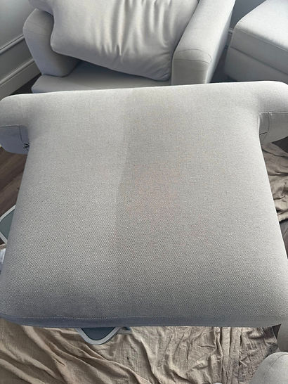 Light gray fabric seat cushion with a distinct clean spot, placed on a drop cloth