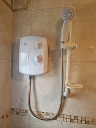 Electric shower installation with handheld showerhead and wall-mounted unit.