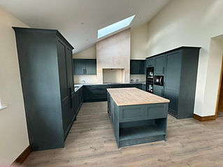 Renovated kitchen with green cabinetry, island and vaulted skylight ceiling