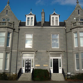 Restored heritage stone building featuring symmetrical facade and elegant entrances.