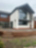 A house featuring a large window and a textured brick wall, showcasing a blend of modern and traditional architecture
