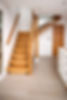 Wooden floating staircase in a modern home interior, leading up from a light laminate floor