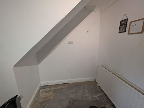 Freshly painted under-stairs area with clean walls and radiator installed
