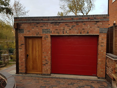 Traditional brick garage with red roller door and wooden side entrance