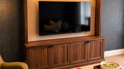 A cozy living room features a wooden entertainment center with a TV, vases, and books