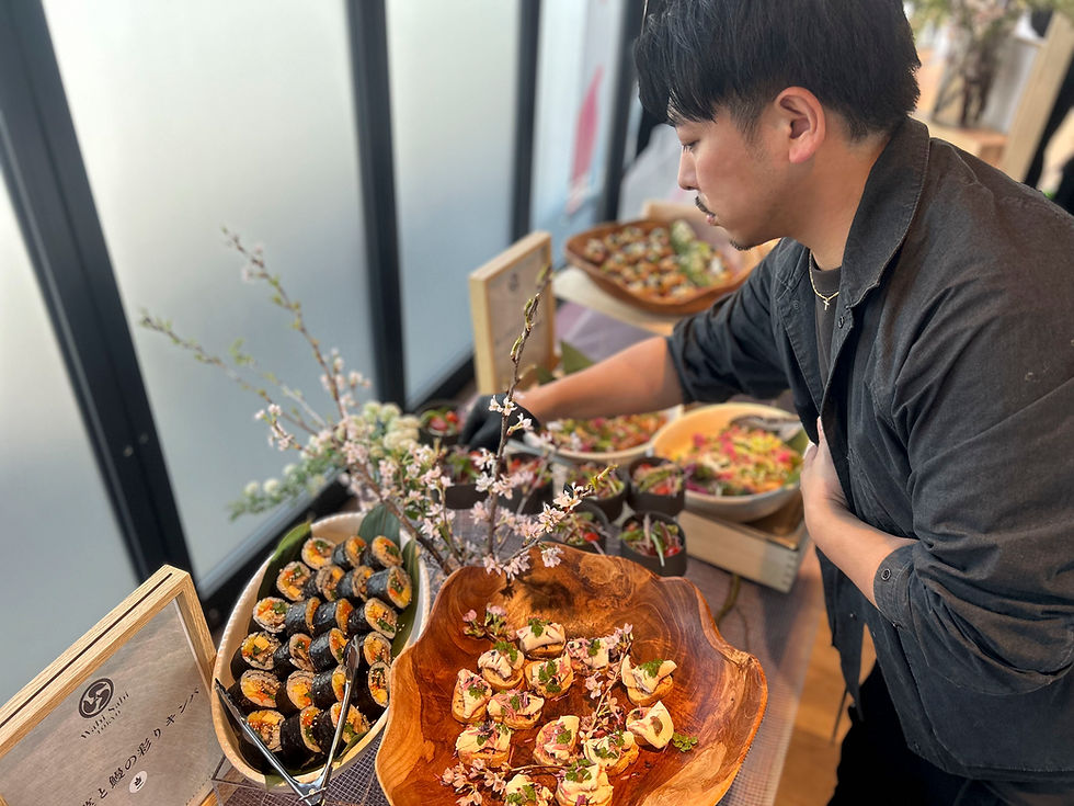 料理家「寺井幸也」がカラフルな料理や桜などを並べ、ケータリングを設置している。春らしい雰囲気。