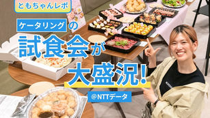 笑顔の女性が社内のケータリング試食会で料理を前にポーズ。ピザやサラダ、スイーツが並び、「ともちゃんレポ」「試食会が大盛況！」「@NTTデータ」の文字。