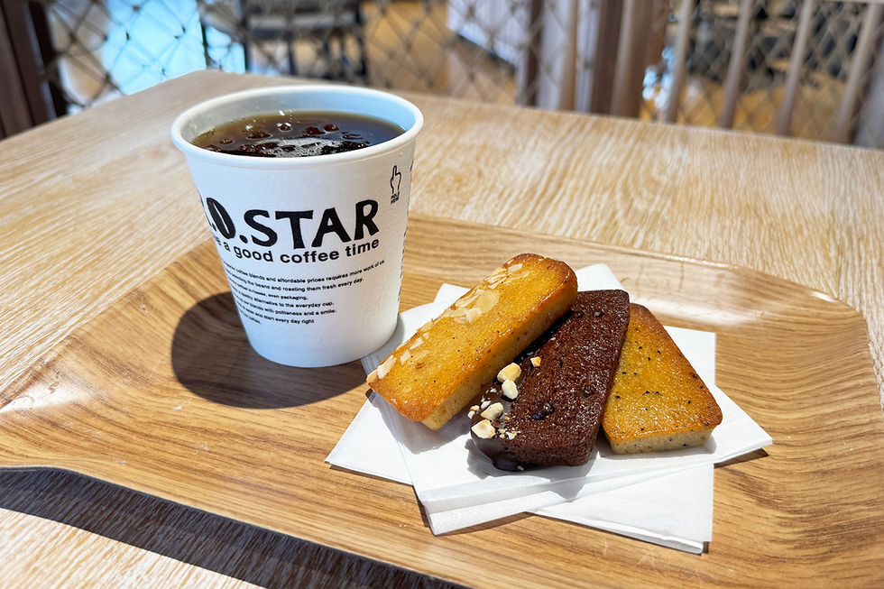 木製トレーに、R.O.STARと書かれたカップのアイスコーヒーと3つのフィナンシェ。明るいカフェでくつろいだ雰囲気。