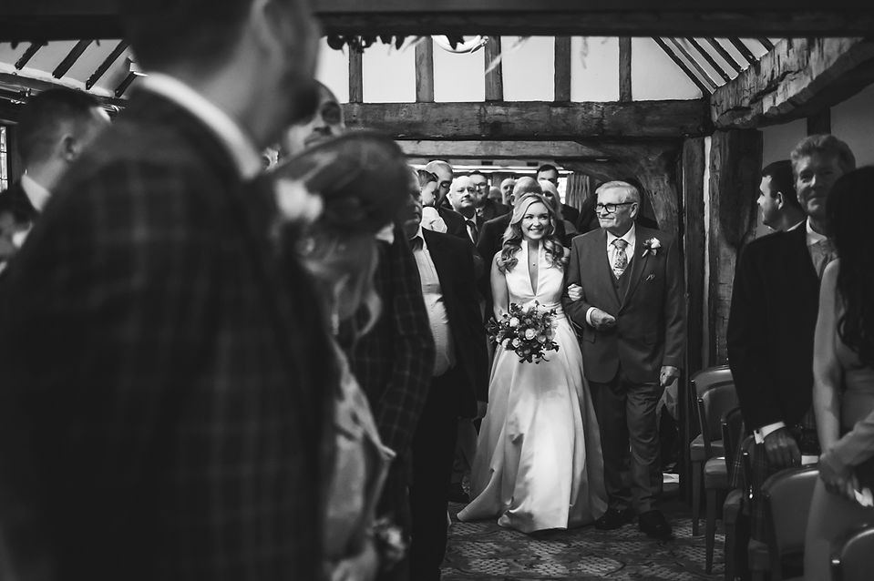 Bride being escorted down the aisle at the Talbooth Restaurant for her wedding ceremony