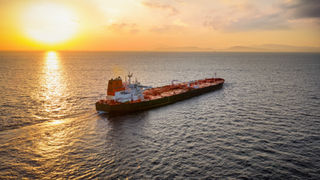 A crude oil ship on the sea at sunset
