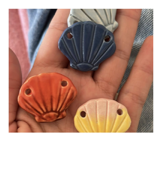 Mão a segurar conchas de cerâmica pintadas à mão no estúdio