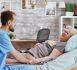male-caregiver-talking-with-sick-old-lady-lying-hospital-bed-he-takes-hand-woman.jpg