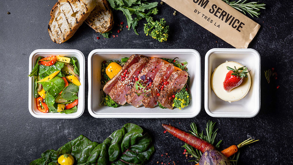 Containers of Room Service food - Tuna, salad and dessert on a dark marble table