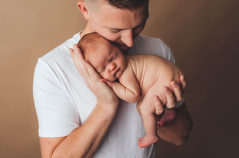 father holding newborn baby in his hands under chin