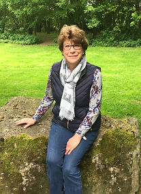 Female pet and housesitter, living in Wiltshire sitting on a rock with green grass behind