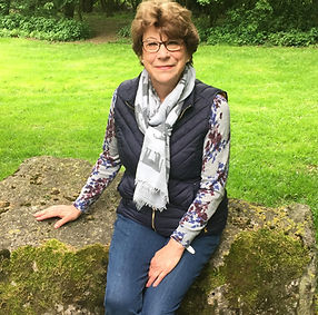 Female pet and housesitter, living in Wiltshire sitting on a rock with green grass behind