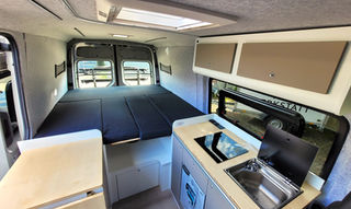 Überblick des Innenraums mit aufgebautem Bett im VW Crafter Individualausbau