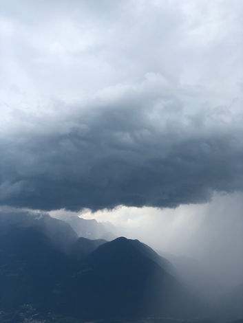 mountains below a huge mountain of clouds, all in a very blue hue