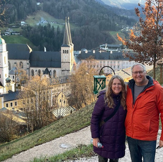 people on a mountain path overlooking a church in a village