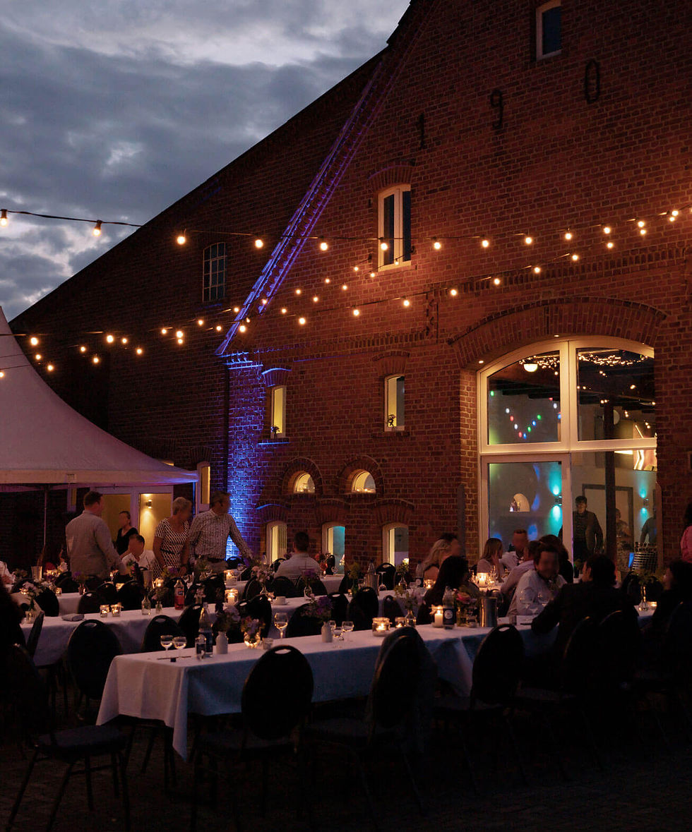 Abendszene vom Innenhof des Kultourhof Raestrup mit gemütlichen Lichterketten über den Tischen
