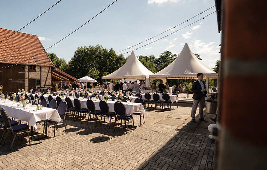 Der Innenhof vom Kultourhof Raestrup mit Cateringzelten, aufgebauten Tischen und der Fachwerkscheune im Hintergrund